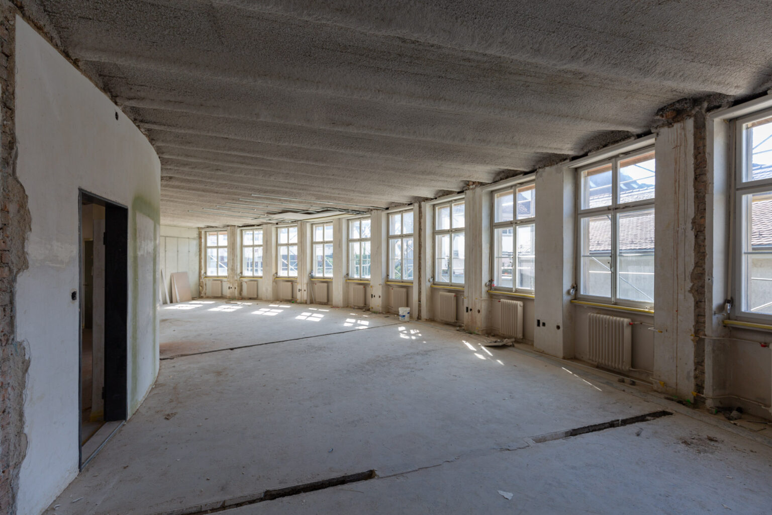 Wo die Mitarbeitenden zuvor in Einzelbüros arbeiteten, befinden sich heute Flex-Arbeitsplätze in Grossraumbüros. Und die beeindruckende Raumwirkung kommt endlich zur Geltung. © Armin Schärer : Architektur Basel