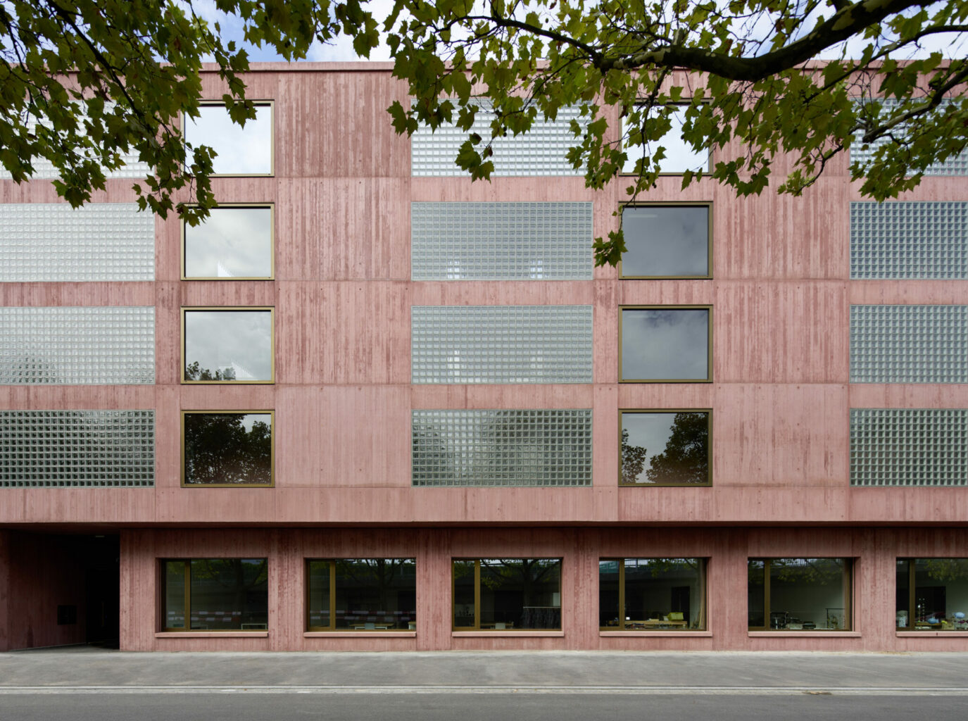 ARGE GP Galli Rudolf Architekten | Proplaning: Wohn- und Gewerbehaus Erlenmatt Ost, Basel 2017. Die Schutzwand aus rot eingefärbtem Sichtbeton mit Glasbausteinen bildet einen Lärmpuffer zur hochfrequentierten Strasse. Foto: Ralph Feiner