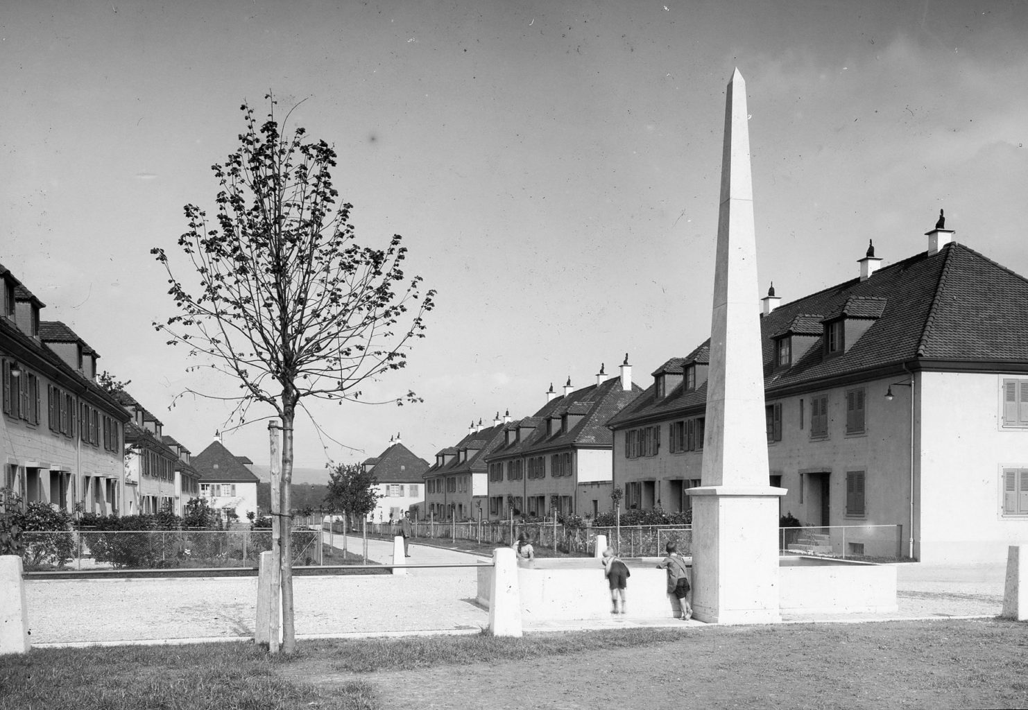 Blick vom Genossenschaftsplatz in Richtung Nordosten mit dem Obelisken im Vodergrund © Siedlungsgenossenschaft Freidorf