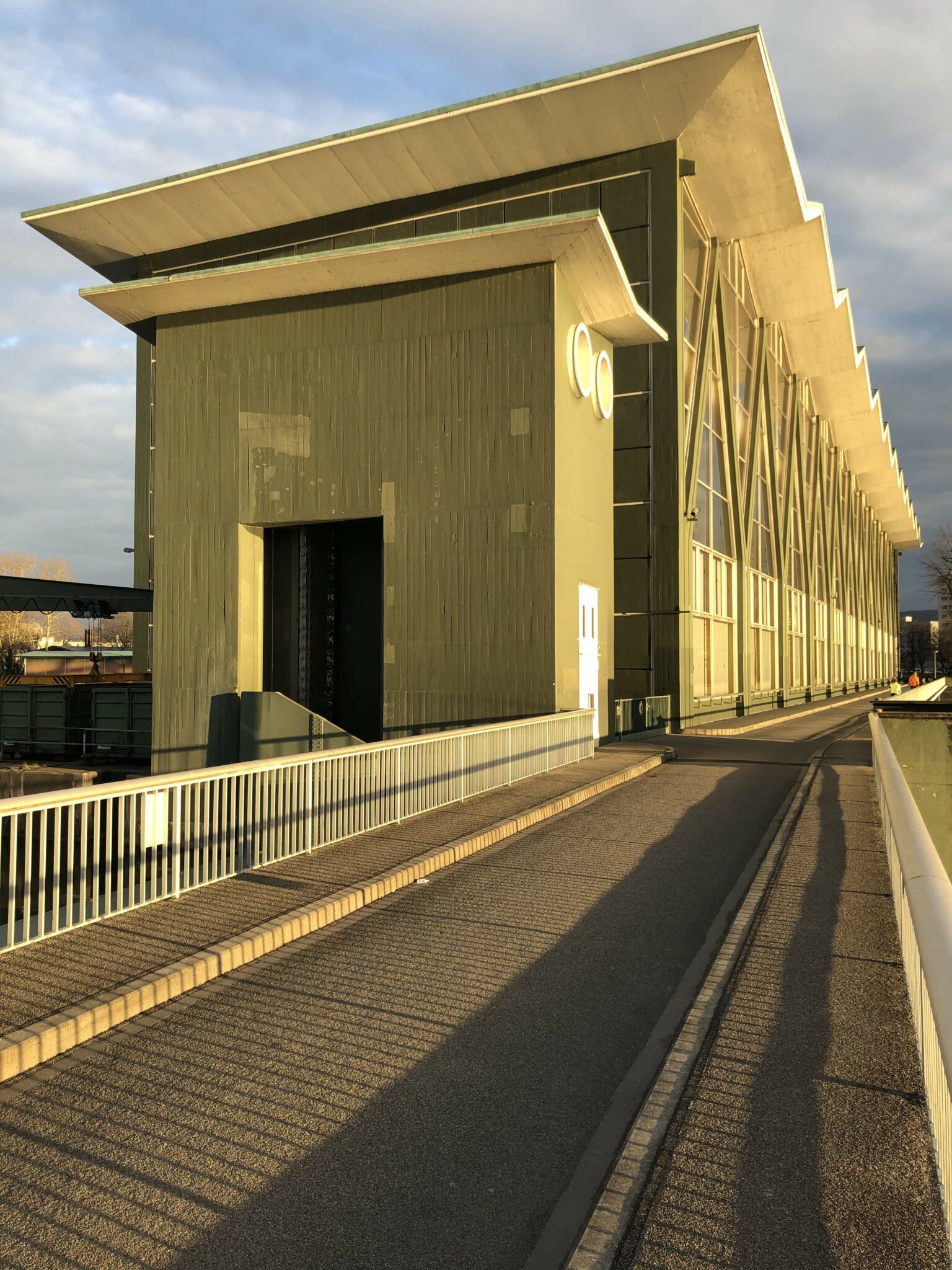Fussgänger und Veloweg entlang des sonnenbeschienenen Kraftwerks