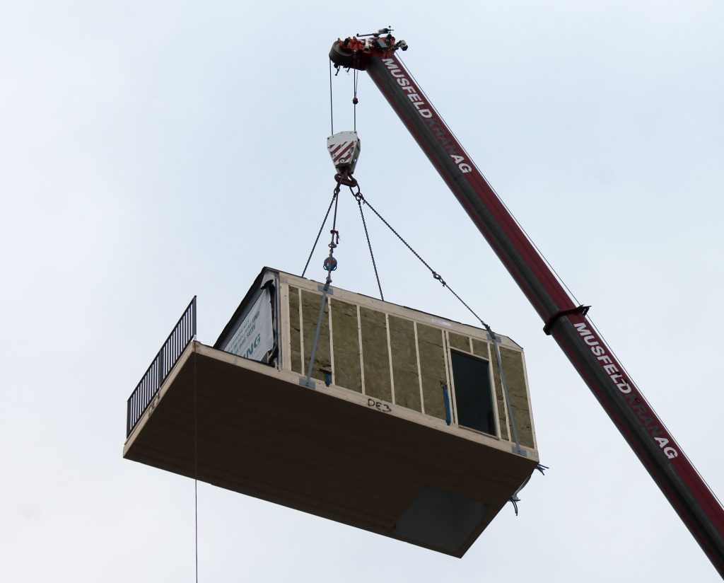 Per Kran werden die Holz-Module auf das Haus gesetzt