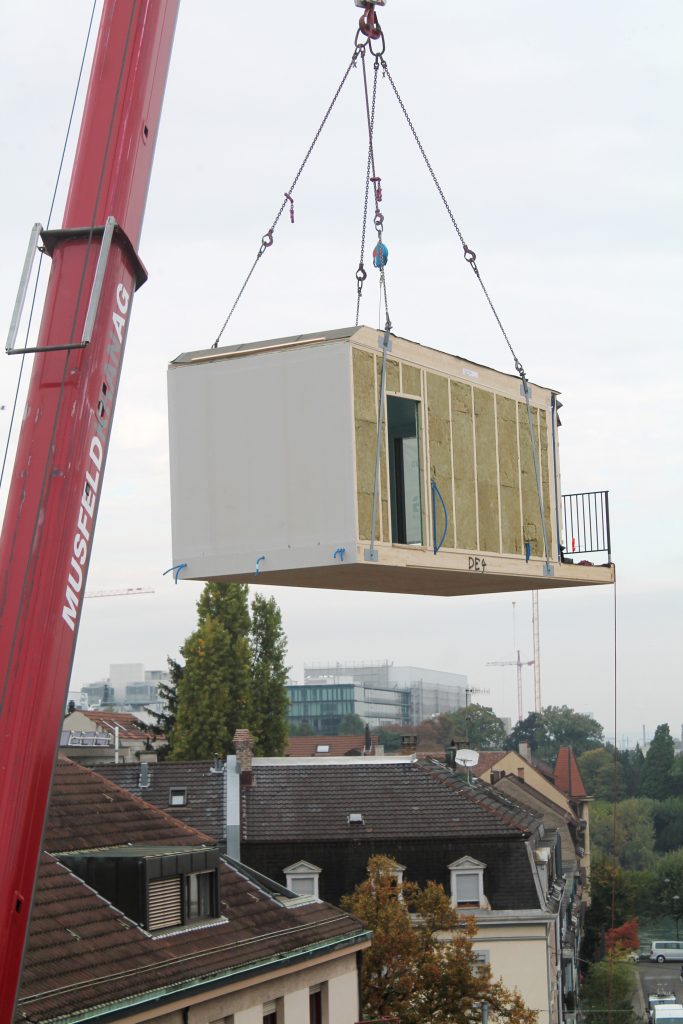 Mit Leichtigkeit hebt der Kran das Holz-Modul über das Breite-Quartier