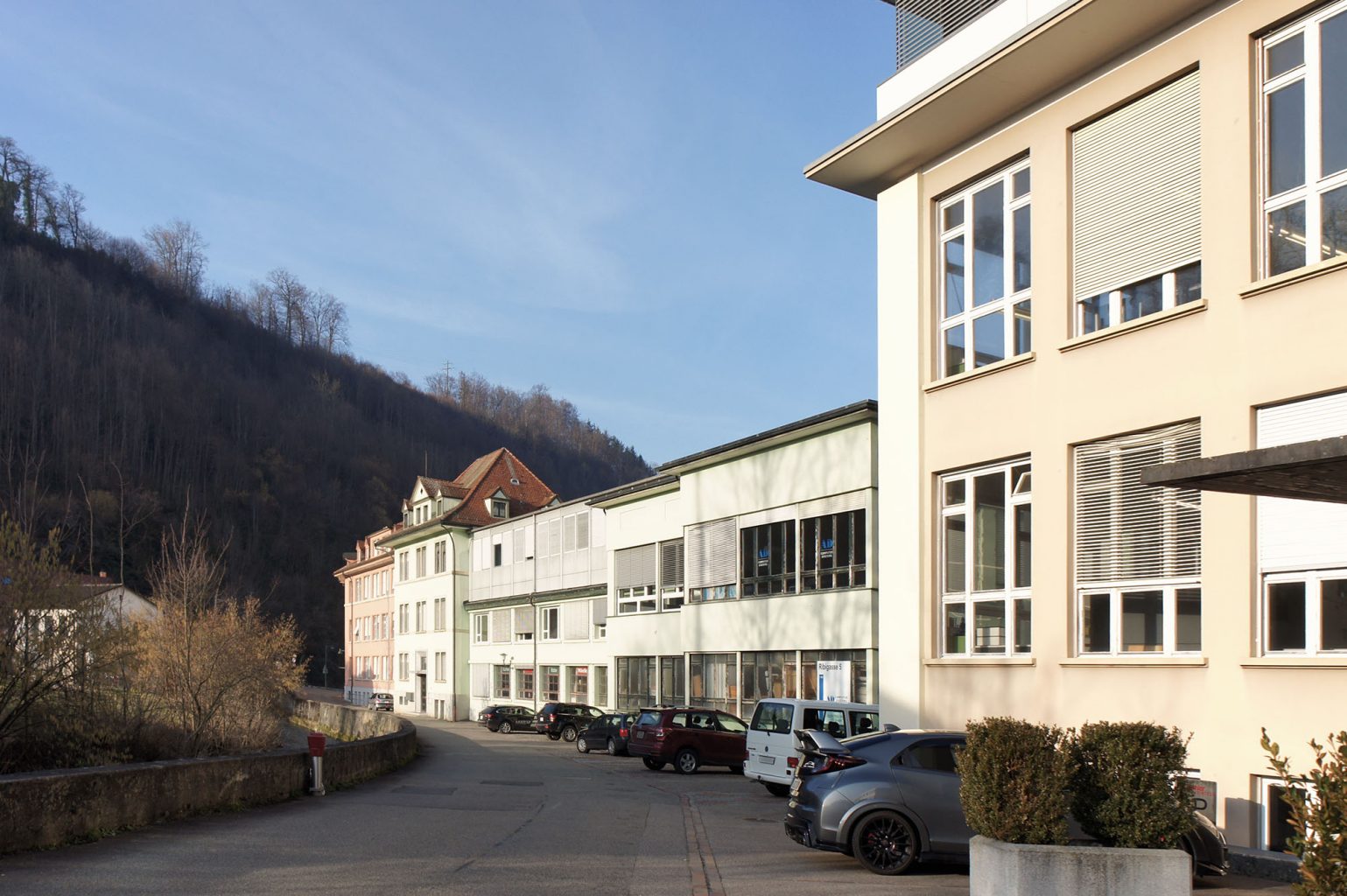 Gesamte Entwicklung: blassrosa (links), blassgrün (mitte), sandbraun (rechts), mit fragwürdigen Dachaufbauten in Metall, Hölstein © Architektur Basel