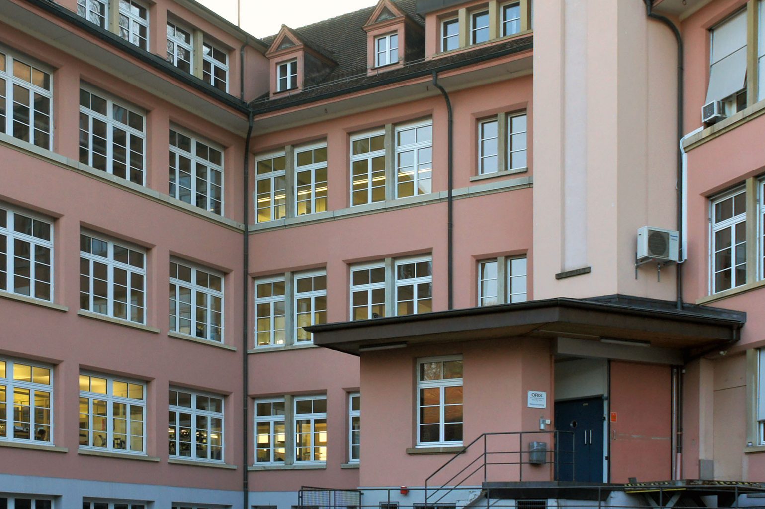 Anlieferung mit Lift, fein unterteilte Fassade mit ausgebauten Walmdächern, Hölstein © Architektur Basel