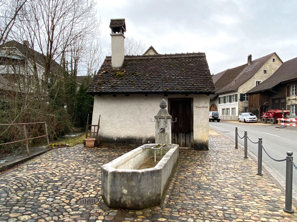 Buuchhüsli Nr. 75 mit Brunnen, giebelseitig zur Hauptstrasse, Ziefen © Simon Heiniger / Architektur Basel