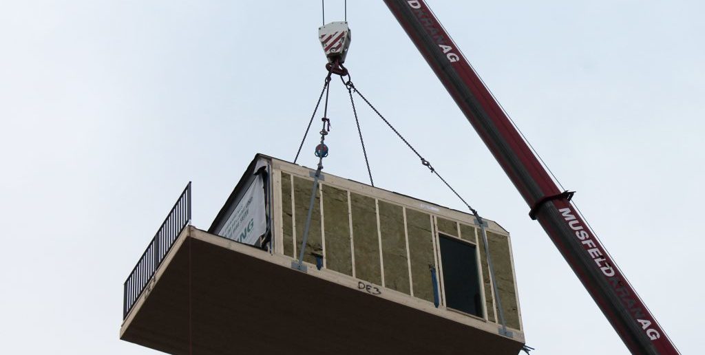 Per Kran werden die Holz-Module auf das Haus gesetzt